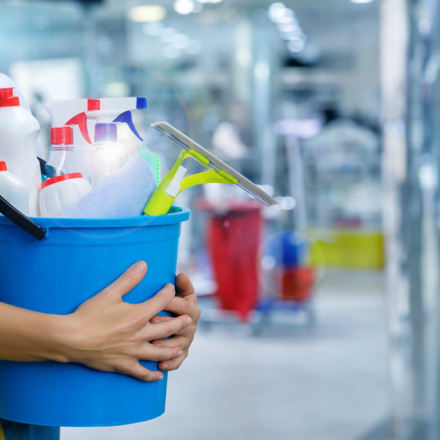 Cleaning lady with a bucket and cleaning products on blurred background.